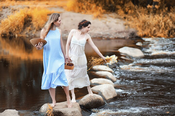 Girls in dresses in autumn on the river