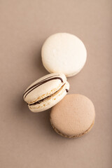 Brown and white macaroons on beige pastel background. top view, close up.