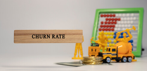 Churn rate written on wood. Money and business machines in the background. Economy and finance.