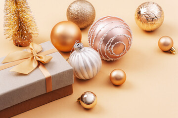 Golden Christmas baubles and gift box on beige background. Winter holidays concept. Top view