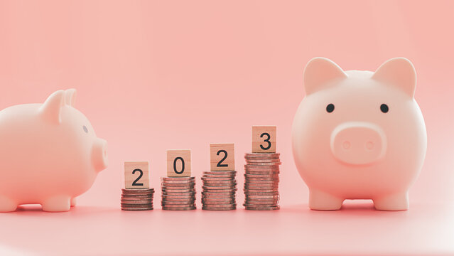 Text of 2023 number written on wooden blocks with coins stacks  and blur of pink piggy bank on pink background, Business and Saving money for new life new year concept, Selective focus.