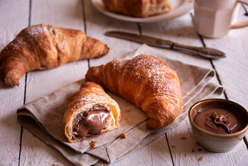 Delicious sweet croissant with chocolate on white wooden table