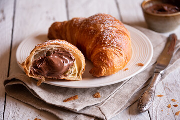 Delicious sweet croissant with chocolate on white wooden table