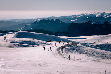 Panoramic view over the ski slope Poiana Brasov ski resort in Transylvania, Pine forest covered in snow on winter season,Mountain landscape in winter with the Bucegi Mountains in the background.
