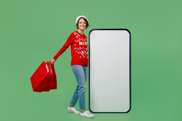 Full size merry young woman in xmas sweater Santa hat posing big huge blank screen mobile cell...