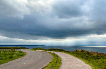 The road with a view of the cloudy sky and the sea. Plévenon, Cap Frehel, Bretagne, France. 