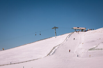 Panoramic view over the ski slope Poiana Brasov ski resort in Transylvania, Pine forest covered in snow on winter season,Mountain landscape in winter with the Bucegi Mountains in the background.