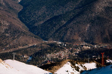Panoramic view over the ski slope Poiana Brasov ski resort in Transylvania, Pine forest covered in snow on winter season,Mountain landscape in winter with the Bucegi Mountains in the background.