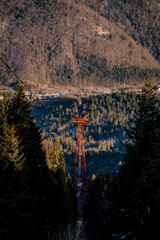 Panoramic view over the ski slope Poiana Brasov ski resort in Transylvania, Pine forest covered in snow on winter season,Mountain landscape in winter with the Bucegi Mountains in the background.