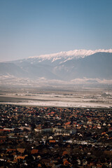 Panoramic view over the ski slope Poiana Brasov ski resort in Transylvania, Pine forest covered in snow on winter season,Mountain landscape in winter with the Bucegi Mountains in the background.