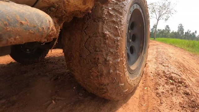 4x4 off road Pickup car wheels are running on a dirt road. Off-road truck car wheels moving on the dirty road with dust, wet and dry mud.  Point of view 4WD truck tire travel in the backcountry place