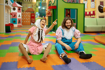 Funny man and woman sitting on playroom floor