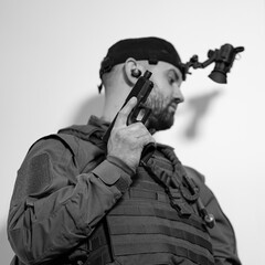 A soldier with a pistol and a night vision device during a mission in a building, black and white...