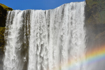 Splashes, water and a rainbow at the Sk&oacute;gafoss waterfall close up in Iceland on a summer sunny day