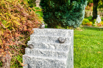 Grabstein in Form einer Treppe mit kleinen Vögeln auf einem Friedhof in Wülfrath