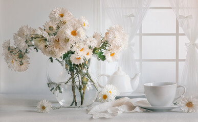 Still life with a bouquet of chrysanthemums and tea in a white mug