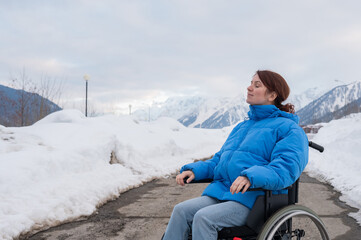 Caucasian woman in a wheelchair travels in the mountains in winter.