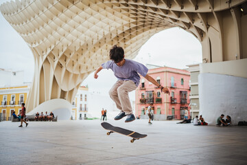 Young man practicing skateboarding in the middle of the city. He is doing a pop shove it