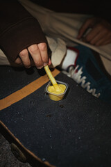 Fototapeta na wymiar Close up of skater teenager dipping a french fry in honey mustard sauce that is on a skateboard