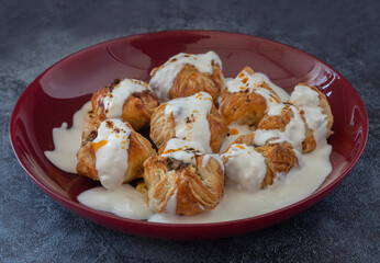 Ravioli made with puff pastry with yoghurt and tomato sauce on the plate; Turkish name (Sosyete ravioli)