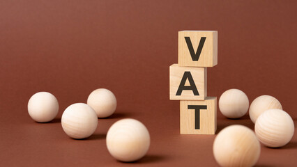 wooden blocks with text VAT on brown paper, business concept. VAT - short for Value Added Tax