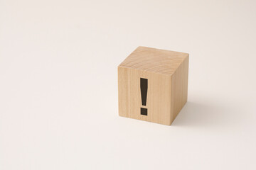 exclamation mark sign drawn on wooden block over white background with copy space.