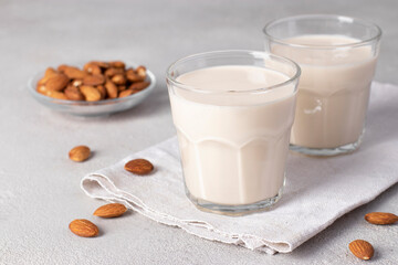 Fresh almond milk in two glasses on light gray table, Healthy vegan milk replacer