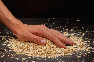 Male hands pouring muesli on a black background