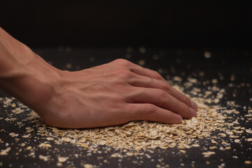Male hands pouring muesli on a black background