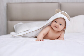 adorable baby girl lies on a white bed with a towel