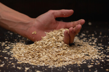 Male hands pouring muesli on a black background