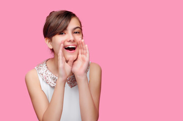 Teen girl in a pink studio making horn with hands announcing loud