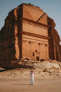 Vertical shot of a man standing in front of the Tomb of Lihyan son of Kuza in Saudi Arabia