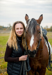 Fototapeta premium portrait of a woman with horse in autumn meadow