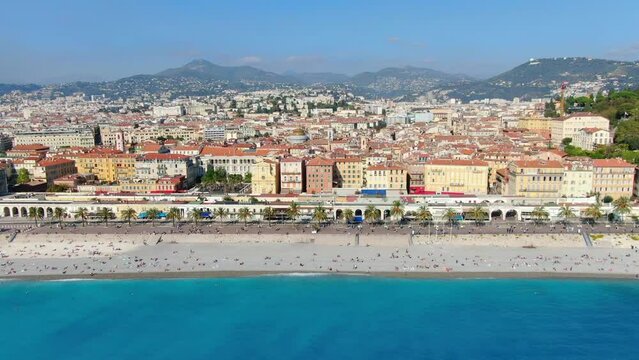 Beautiful panorama of English Promenade in Nice, France. Palm trees, old houses in Old Town Azure Sea And Green Hills. Summer in French Riviera. View from sky, Drone video 