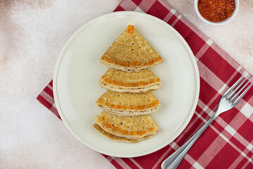 Christmas and New year tree shaped pancakes or crepes with red caviar decorations on light colored background. Holiday homemade food. Flat lay top view. Christmas food for children and kids.