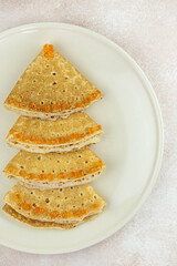 Christmas and New year tree shaped pancakes or crepes with red caviar decorations on light colored background. Holiday homemade food. Flat lay top view. Christmas food for children and kids.