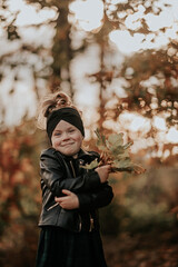 Dziewczynka trzyma w garści kilka jesiennych liści - obrazy, fototapety, plakaty