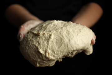 Liquid sourdough in hands on a black background, flowing dough.