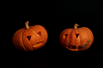 spooky concept - two jack-o-lanterns isolated on black background. Image contains copy space
