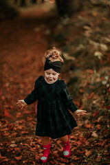 Mała dziewczynka bawi się w jesiennych liściach w lesie © ZiraPhoto