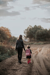 Mama odprowadza córkę z plecakiem do przedszkola