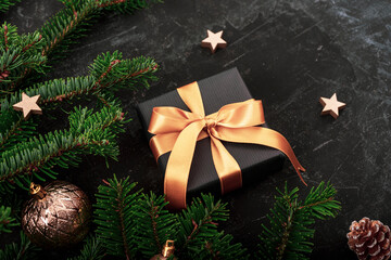 Black gift box, Christmas baubles, stars, fir tree and fir cone on black background. Winter holidays concept. Top view, flat lay