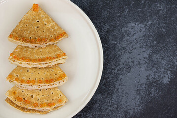Christmas and New year tree shaped pancakes or crepes with red caviar decorations on dark...