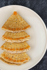 Christmas and New year tree shaped pancakes or crepes with red caviar decorations on dark background. Holiday homemade food. Flat lay top view. Christmas food for children and kids.
