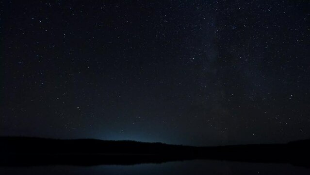 The time lapse of the night starry sky. night landscape of the Milky Way over the lake.