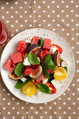 Overhead view of watermelon slices tomatoes salad fig cheese