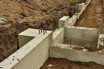 Concrete footings and foundation with anchor bolts ready for further construction.