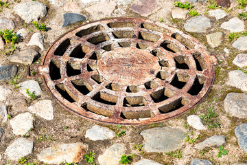 Rusty metal manhole cover on urban pavement road