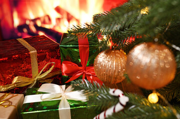 a lot of boxes with Christmas gifts on a wooden table against the background of a Christmas tree and a fireplace.